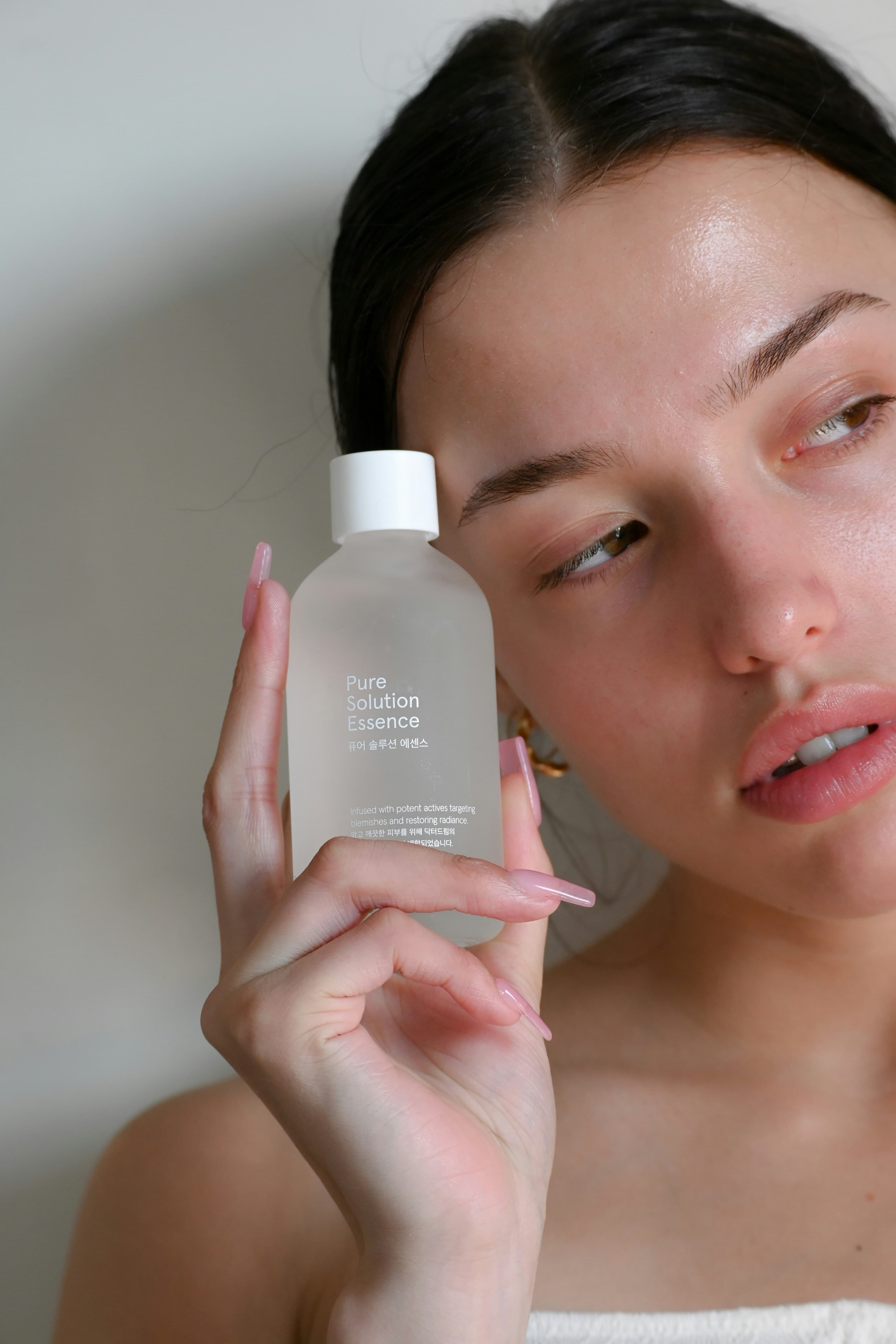 Woman presenting a skincare bottle to camera